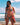 Woman in a bikini standing on a beach with ocean and sky in the background