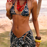 Woman in a patterned bikini and cover-up standing on a beach.