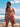 Woman in a bikini standing on a beach with ocean and sky in the background