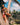Woman in a bikini standing next to a palm tree with a scenic background