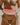 Woman in a colorful bikini holding a watermelon slice on a beach.