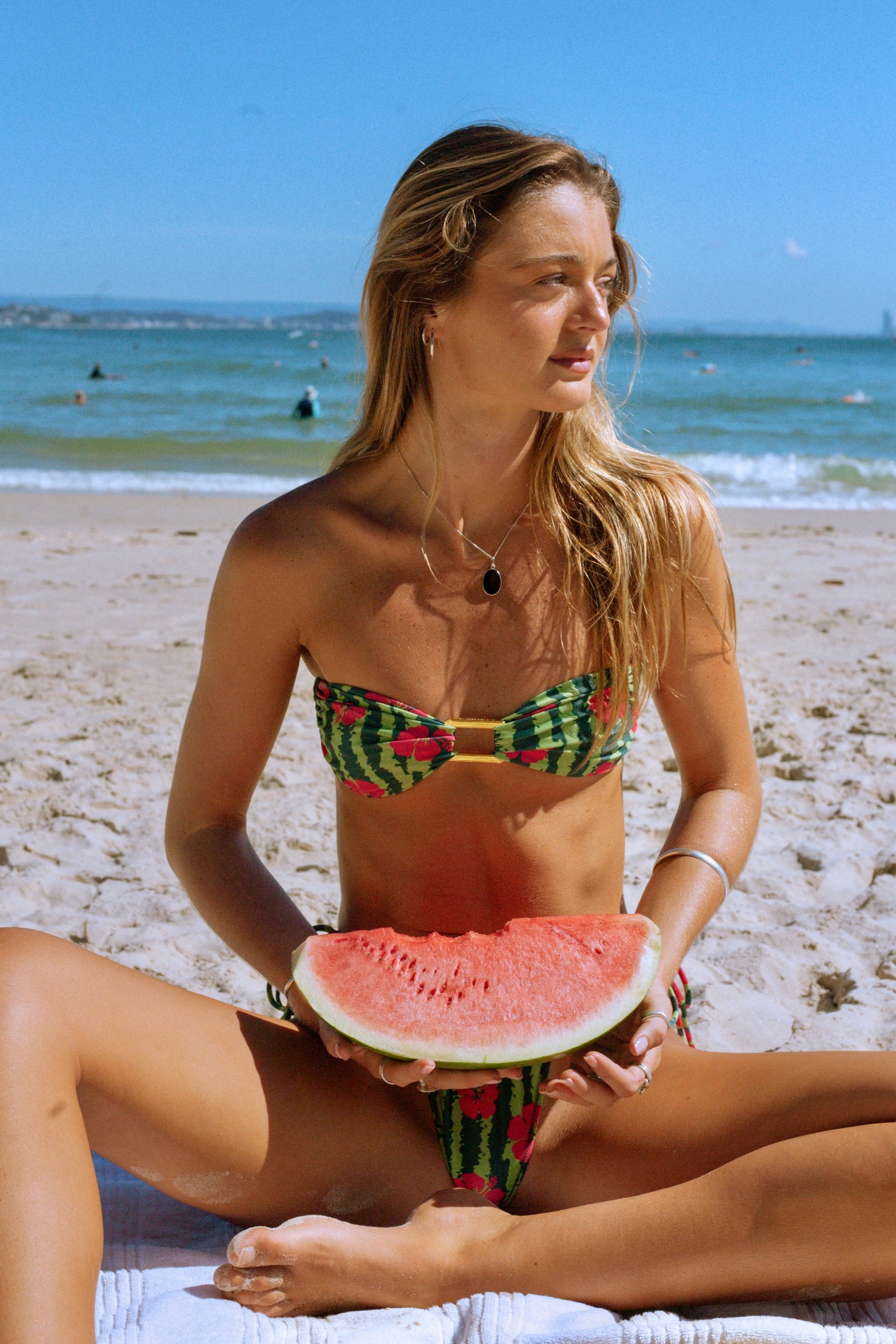 Woman in a bikini holding a watermelon slice on a beach
