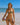 Woman in a watermelon-patterned bikini on a beach with a clear blue sky.