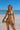 Woman in a watermelon-patterned bikini on a beach with a clear blue sky.