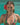 Woman in a floral bikini with a red flower in her hair, standing in clear blue water.